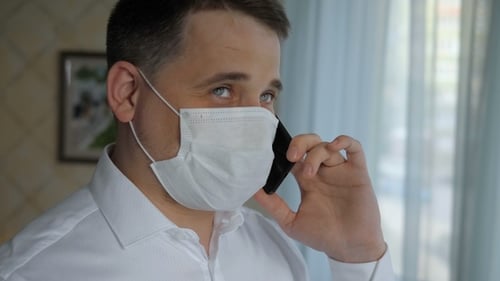 Man with mediucal mask on talking on mobile phone. Working