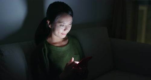 Woman Using Smartphone in Dark Room at Night