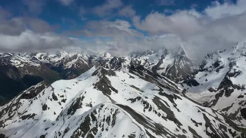 Air Flight Through Mountain Clouds Over Beautiful Snowcapped Peaks of Mountains and Glaciers