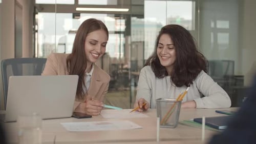 Smiling Women Discussing Data in Office Setting