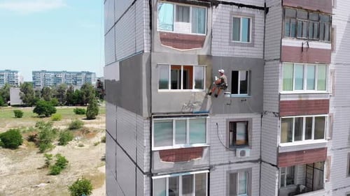 Vista aérea: dois alpinistas industriais realizam trabalhos em edifícios de fachadas de isolamento