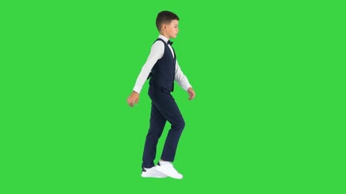 Little Boy in a Bow Tie and Waistcoat Walking Waving His Hands on a Green Screen Chroma Key