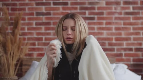 Une fille malade avec un foulard autour du cou, enveloppé dans une couverture et se frotte les épaules au réchauffement