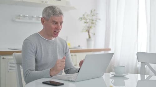 Man Video Conferencing on Laptop in Bright Kitchen