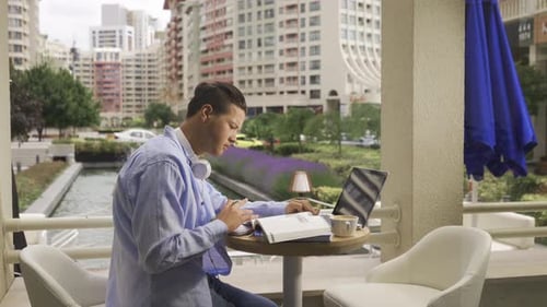 Young Adult Studying at an Outdoor Cafe