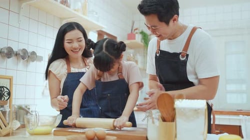Asian happy family spending time in kitchen together while staying at home doing homemade bakery.