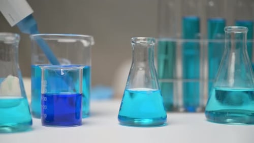 Laboratory Glassware with Blue Liquids Being Poured