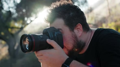 Adult Man Photographing with Camera Outdoors on Sunny Day
