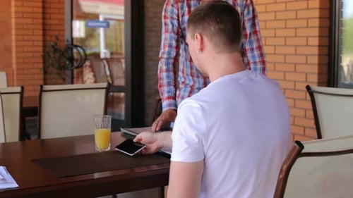 A male customer pays using NFC contactless payment technology on a smartphone.