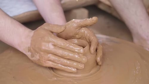 Les mains font de la poterie en argile sur une roue