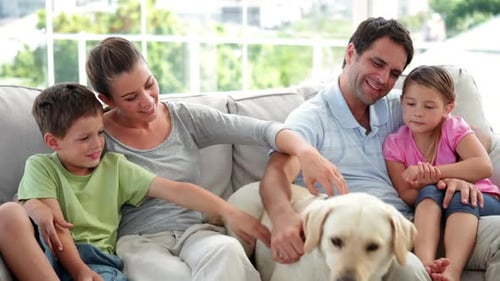 Happy Family Relaxing with Dog on Couch