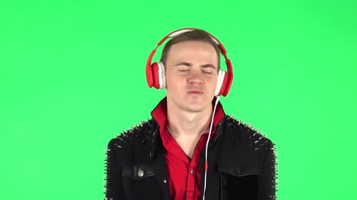 Guy Dancing and Enjoys Music in Big Red Headphones. Green Screen