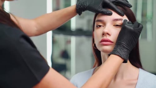 Woman Getting Eyebrows Tinted by Cosmetologist