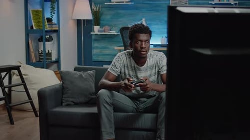 Man Plays Video Game on Couch with Controller
