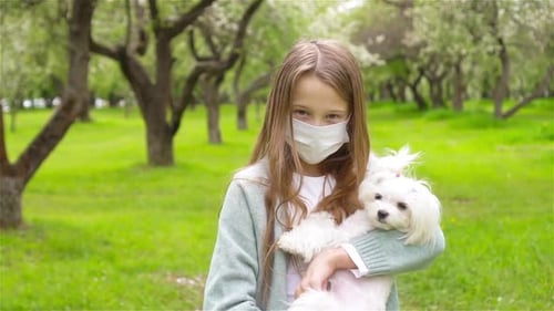 Little Girl with Dog Wearing Protective Medical Mask for Prevent Virus Outdoors in the Park