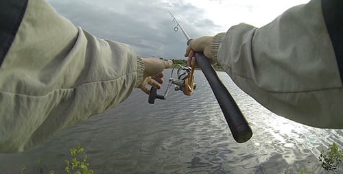 Person Fishing in a Lake on a Cloudy Day