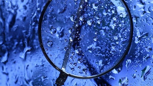 Close-Up of Magnifying Glass with Water Droplets on Blue