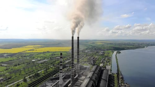 Starker schwarzer Rauch, der aus den Rohren der Wärmestation gegen den blauen Himmel kommt