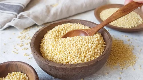Millet Grain Scooped in Wooden Bowl with Spoon