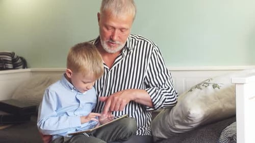 Grandfather and Grandson Using Tablet Together Indoors