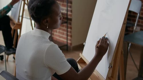 Afroamerikanische Frau, die Objektmodell auf Leinwand und Staffelei zeichnet