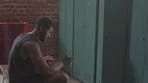 Boxeador masculino envolviendo las manos en el vestuario