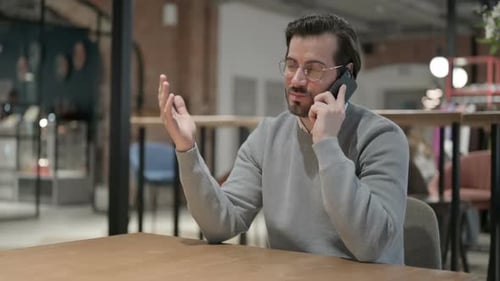 Jeune homme parlant sur smartphone au bureau