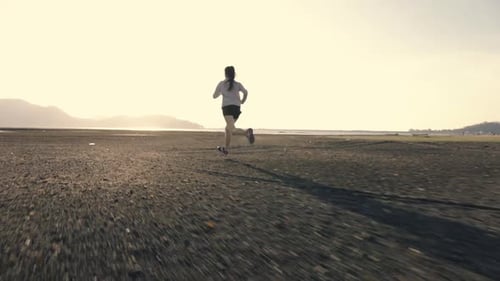 Woman Runs Toward Shoreline in Sunny Field