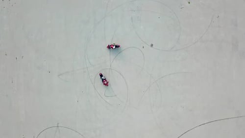 Aerial view of two red motorbikes racing high speed on a road in a circle way.