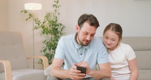 Man and Child Use Smartphone Together at Home