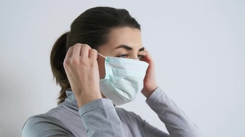 Woman Putting on a Protective Surgical Mask