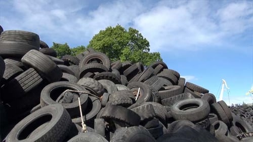 Huge Pile of Discarded Rubber Tires on Sunny Day