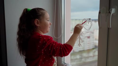 Child draw santa's gnome on window with white paints close-up. Caucasian female person decorate room