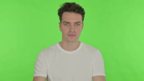 Inviting Young Man Pointing at Camera on Green Background