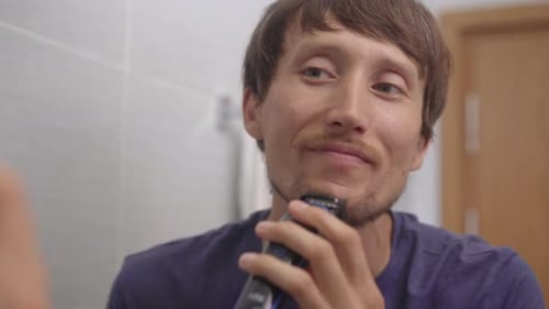 Closeup Shot of a Young Man That Shaves His Beard Using a Beard Trimmer