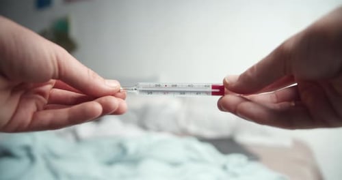Männliche Hände halten analoges Thermometer mit sehr hoher Temperatur