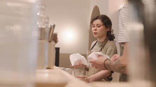 Female Barista Polishing Glassware in Cafe Environment