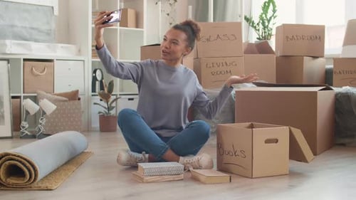 Young Woman Video Chatting in Unpacked Moving Boxes