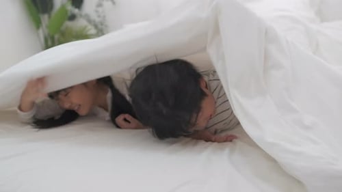 Happy Children Lying on Bed Laughing