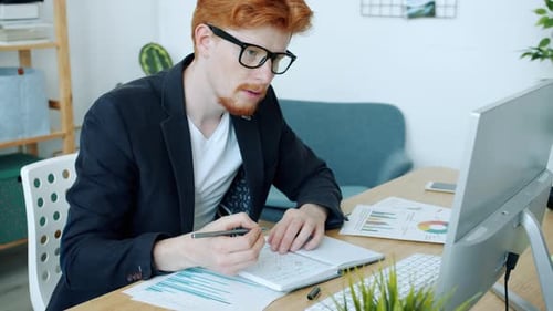 Portrait of Serious Young Businessman Working in Office Writing and Using Computer