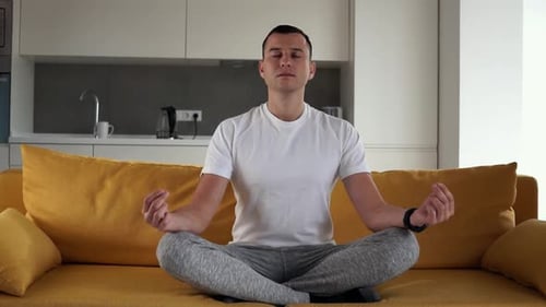 Man Meditating on Couch in Bright Home