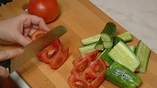 Slicing Fresh Tomato and Cucumber on Cutting Board