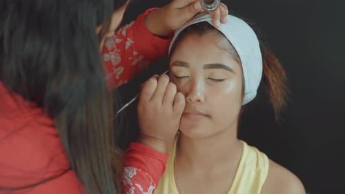 Nahaufnahme einer schönen Frau im Make-up-Studio und Visagistin, die ihre Augenbrauen färbt