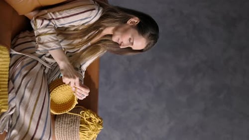 Woman Sits and Crochets a Yellow Yarn Bowl