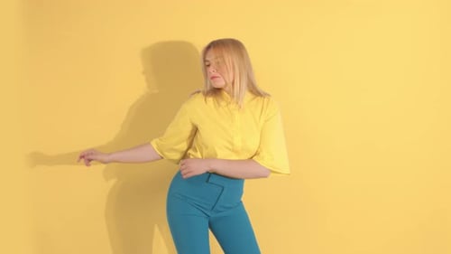 Young Woman in Bright Clothes on Bright Yellow Background in Studio