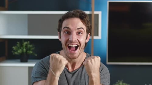Excited young man cheering in his modern living room