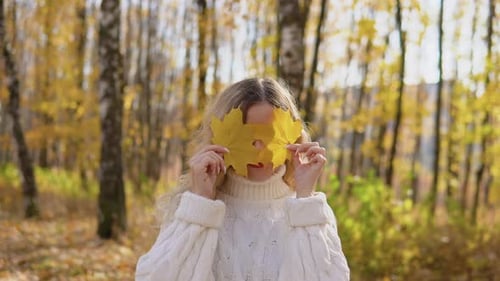 Woman Holding Leaves in Autumnal Forest