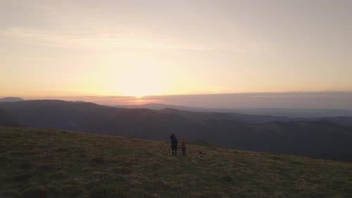 Large Group of Happy Friends on Mountain Top Looking at the Sunset Over Mountain's Valley