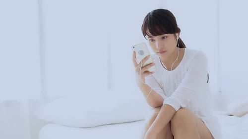 Young Adult Using Phone on Bed Indoors