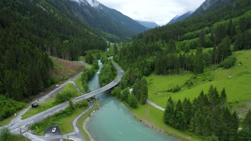 Aerial Footage of Mountain Road Crossing Blue River in Beautiful Apline Forest and Waterfall in